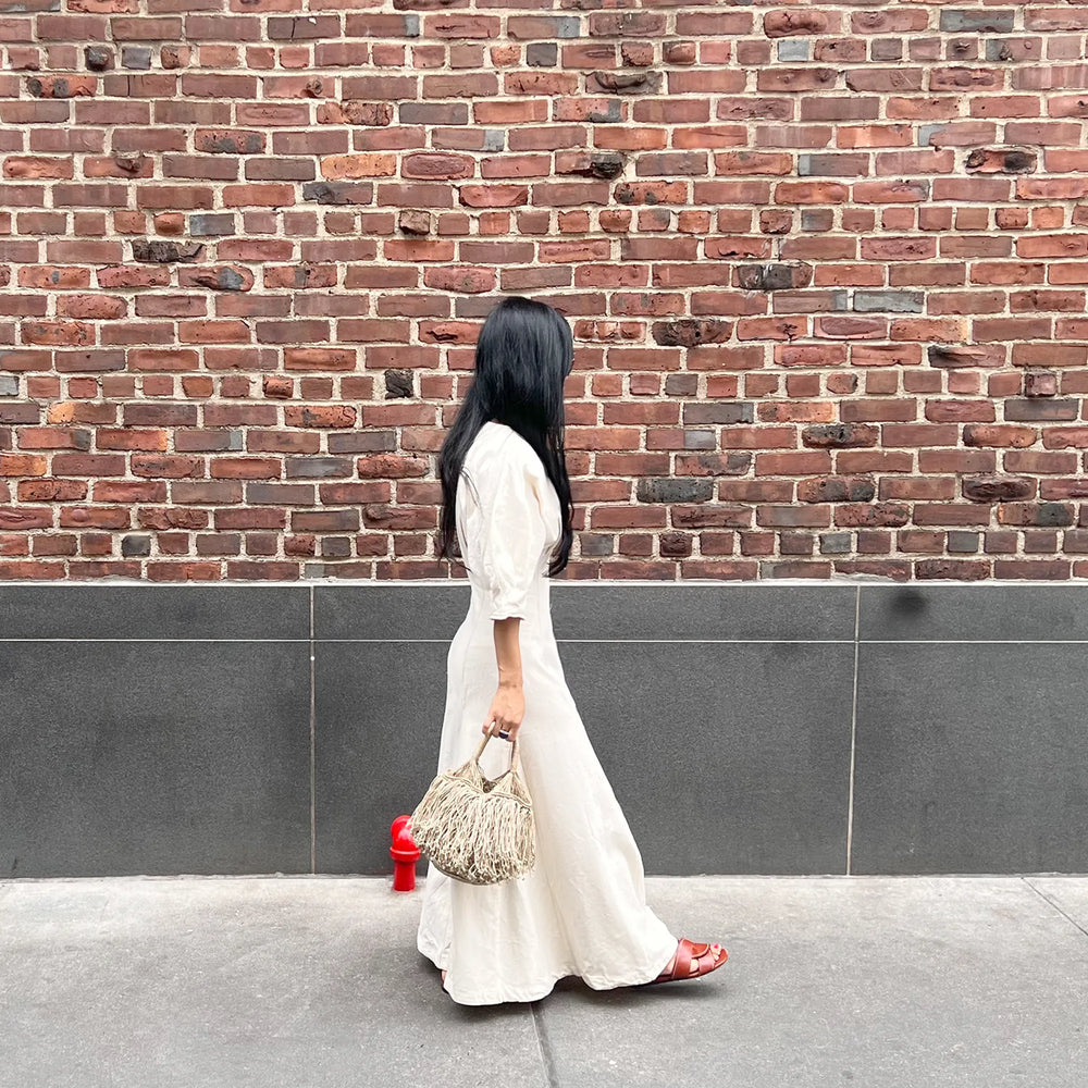 Woman in a white dress standing against a brick wall