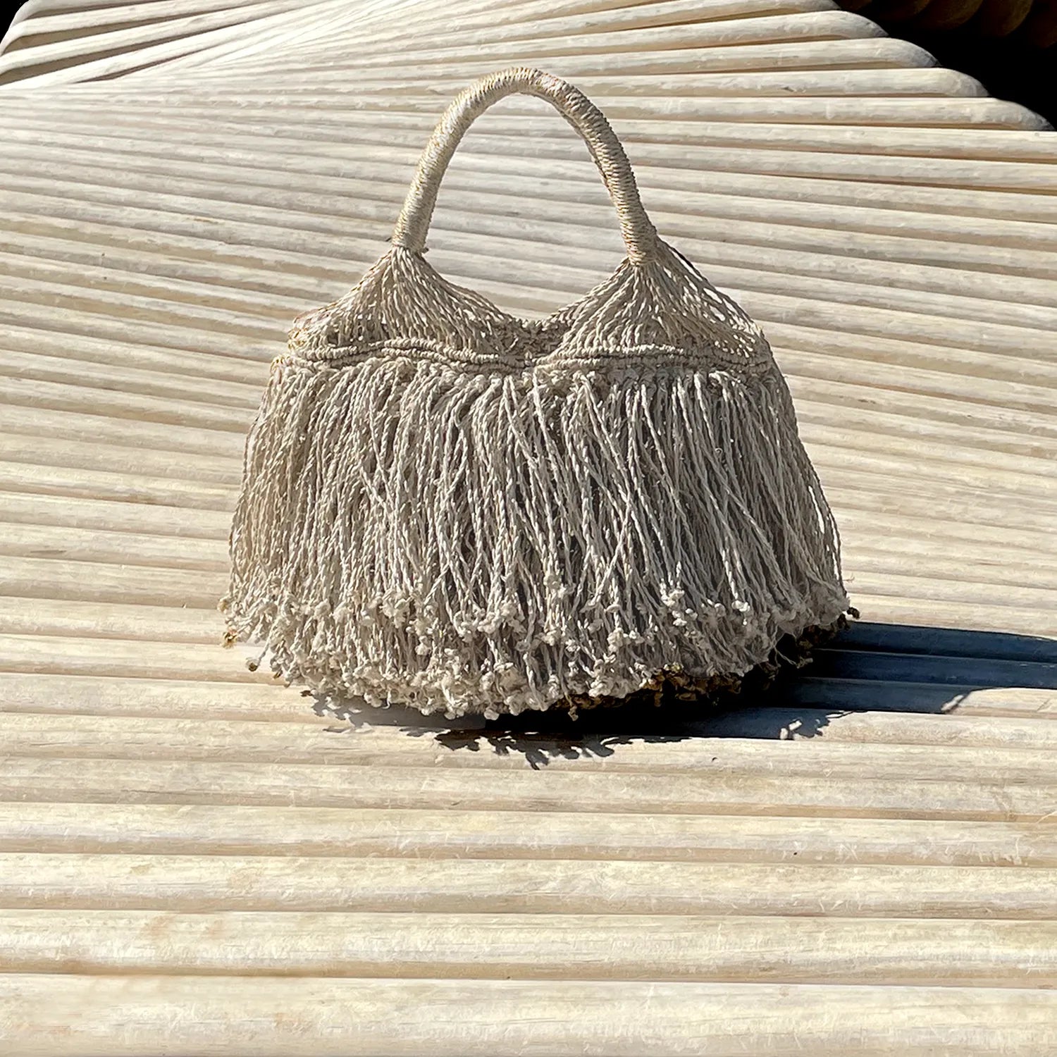 Macrame handbag with fringe on a wooden surface