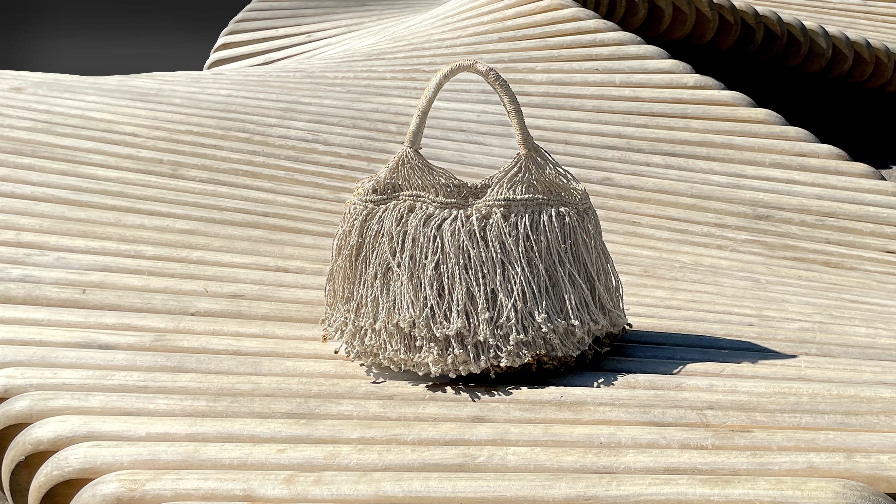 Textured handbag with fringe details on a ribbed surface